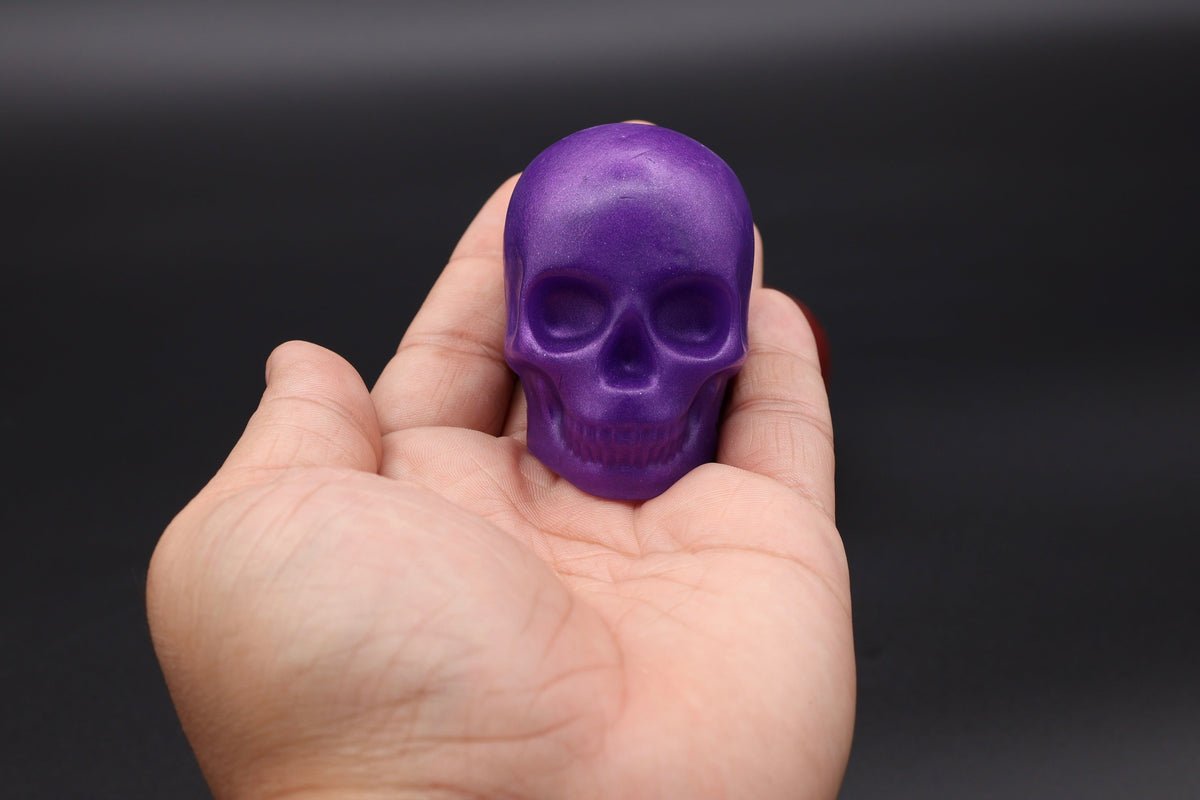 Hand holding a purple skull soap showing size reference